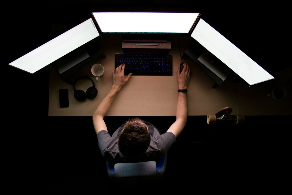 A trader at a desk with three screens, seen from above